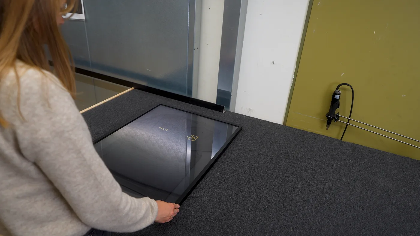 Das Glas wird vorsichtig auf den geöffneten Trikotrahmen gelegt