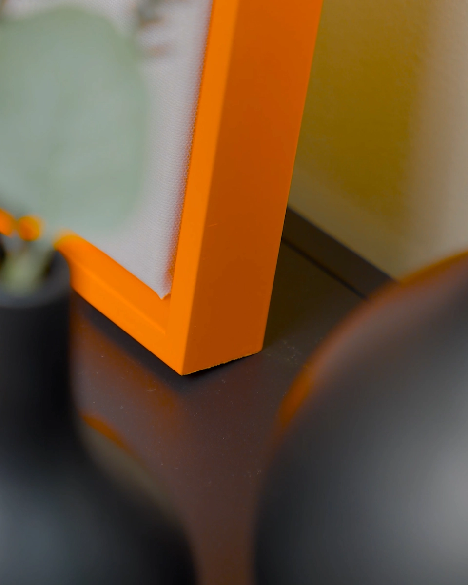 Detailaufnahme der Ecke des Schattenfugenrahmens Jill in leuchtendem Neon-Orange für Leinwandbilder in wohnlichem Ambiente